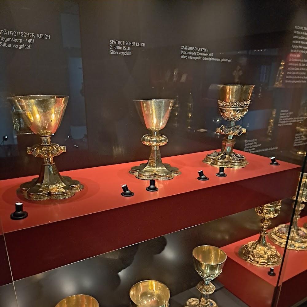 Three silver chalices on a red display.
